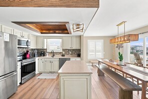 Een moderne keuken met witte kasten, een centraal eiland en een eetgedeelte met uitzicht.