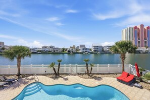 A swimming pool with a view of a body of water and buildings in the background. - Palm Cove | Luxury Channel Home + Coastal Escape (North Myrtle Beach)