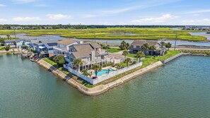 A waterfront property with multiple houses, a dock, and a swimming pool. - Palm Cove | Luxury Channel Home + Coastal Escape (North Myrtle Beach)