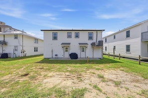 A two-story residential building with a front door, two windows, and a small front yard. - Elvi's Beach House | Spacious 6BR Duplex (North Myrtle Beach)