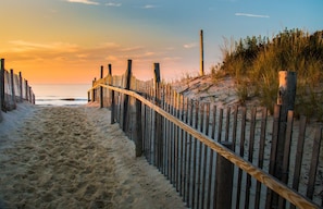 Ein hölzerner Zaun entlang eines Strandwegs mit einem Holzpfosten im Hintergrund, auf dem 'MARINEST' steht.