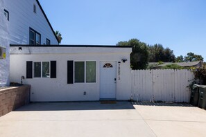 A single-story building with a white exterior, a front door, and a small porch area. - Cozy Casa | Contemporary 2BR Home · La Mesa (La Mesa)