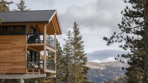 Una baita in legno con un balcone affacciato su una valle boscosa.