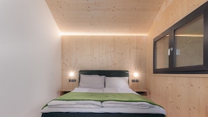 Una camera da letto moderna con soffitto in legno, un letto con coperta verde e due lampade da comodino.