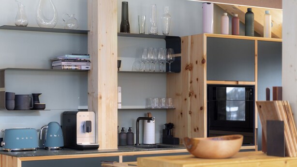 Una cucina con mobili in legno, una macchina da caffè, un tostapane, un forno a microonde e diversi bicchieri su mensole.