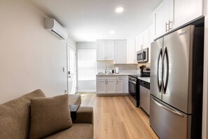 A compact kitchen with white cabinets, a stainless steel refrigerator, and a microwave. - Cozy Casa | Striking Santee Stay (Santee)