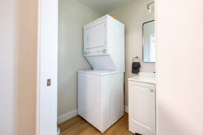 A laundry room with a stacked washer and dryer, a sink, and a mirror. - Cozy Casa | Striking Santee Stay (Santee)