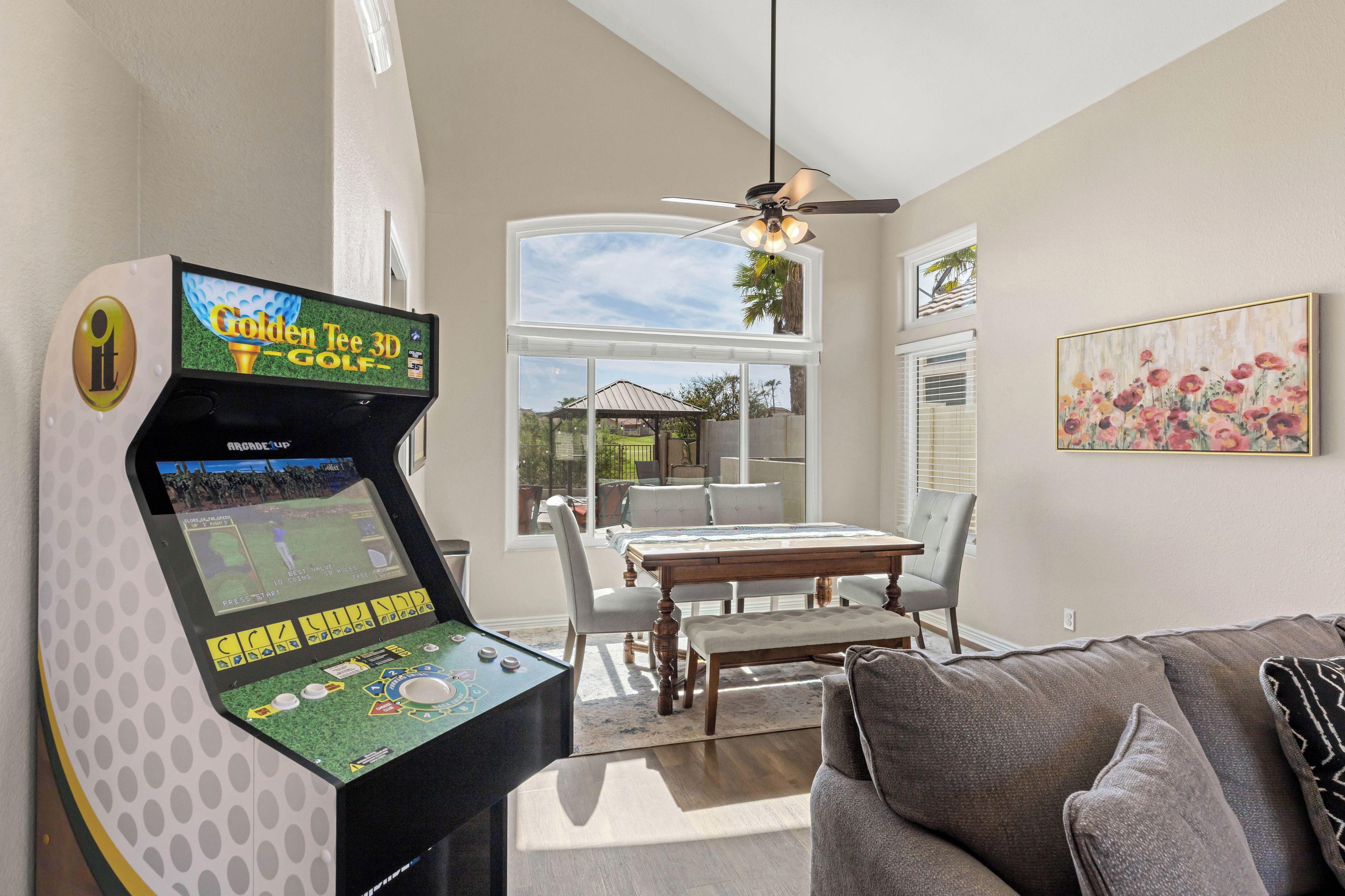 A room with a pool table, a ceiling fan, a dining table with chairs, and a painting on the wall.