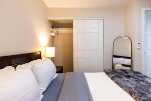 Ein Hotelzimmer mit Bett, Nachttisch, Lampe, Kleiderschrank und Spiegel.