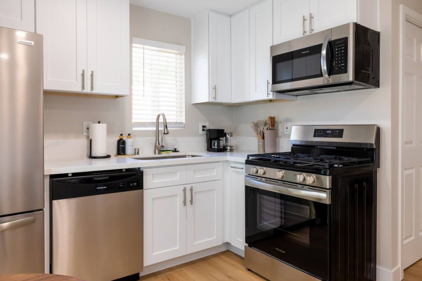 A modern kitchen with stainless steel appliances, white cabinetry, and a built-in microwave.