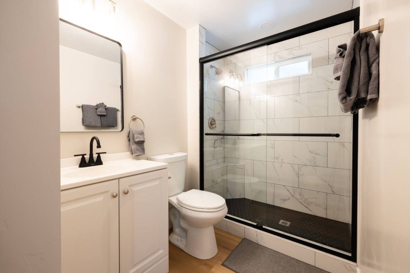 Une salle de bain moderne avec une douche à parois de verre, un lavabo blanc et des toilettes.