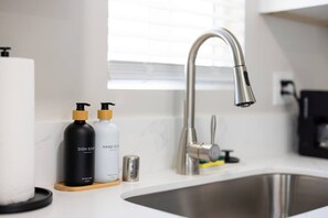Eine moderne Küche mit einer Edelstahlspüle, einem Wasserhahn und zwei Seifenspendern auf der Arbeitsplatte.
