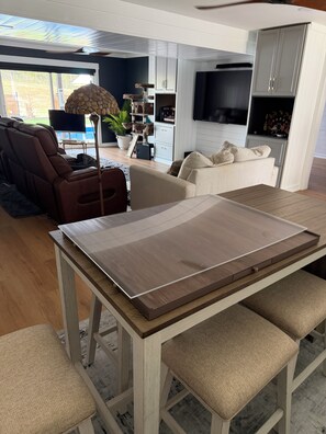 Uma sala de estar moderna com sofá-cama, mesa de jantar com banco, arranhador para gato e televisão.