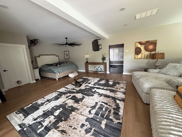 Quarto com cama, ventoinha no teto, tapete e quadro na parede.