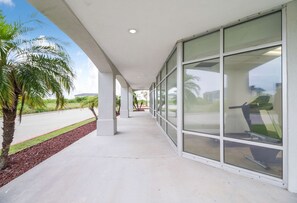 A covered walkway with glass walls, palm trees, and a clear sky. - Budget-Friendly Ingleside Room l Kitchen + Pool Access | Free Parking (Ingleside)