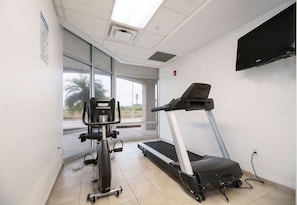 Gimnasio con cinta de correr, bicicleta estática y amplios ventanales.