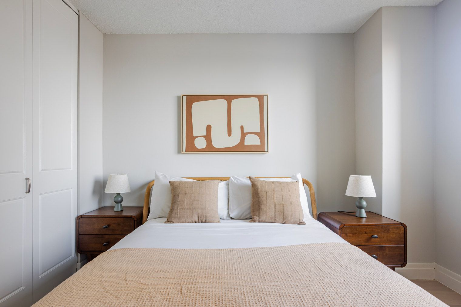 Un dormitorio con una cama grande, dos mesitas de noche y una obra de arte abstracta en la pared.