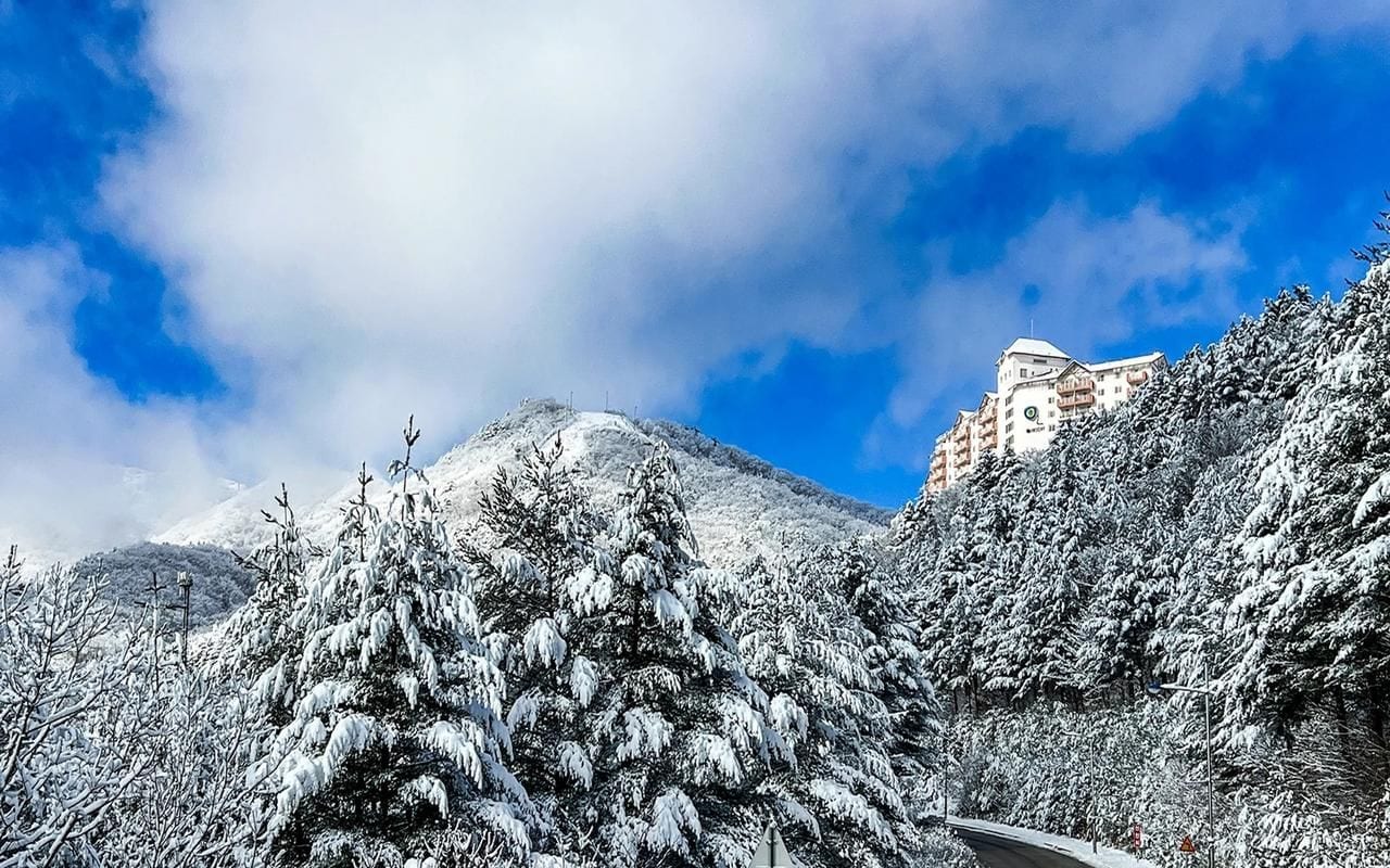 Montanha coberta de neve com um edifício ao fundo.