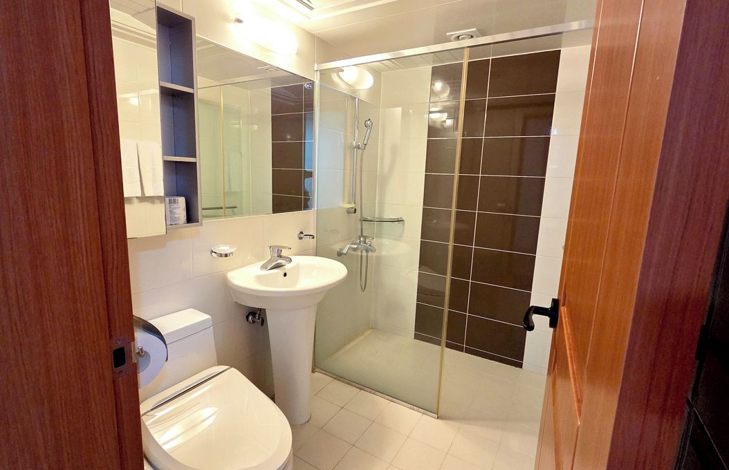 A bathroom with a toilet, sink, and glass-enclosed shower area.