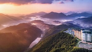 A mountainous landscape with a valley and a building complex with multiple floors and balconies. - O2 Resort (Taebaek)