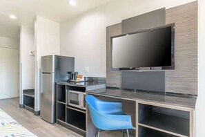 Eine moderne Küche mit integriertem Mikrowellenherd, einem Kühlschrank und einem flachbildschirmigen Fernseher an der Wand.