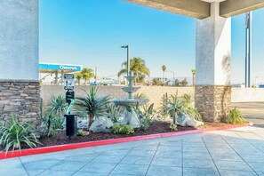 Eine Chevron-Tankstelle mit einer Tierkot-Station, einem Springbrunnen und begrünten Flächen mit Kakteen und Sukkulenten.