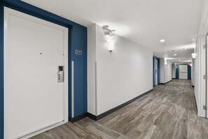 Ein Hotelkorridor mit weißen Türen, blauer Umrandung und Holzboden.