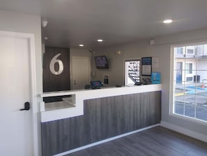 A reception desk with a number '6' sign, a computer, a phone, and a framed welcome sign. - Budget & Pet-Friendly Room | California State Railroad Museum - 2.6 Miles Away (West Sacramento)