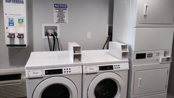 A laundry room with two Whirlpool washers, a notice board, and a utility box.