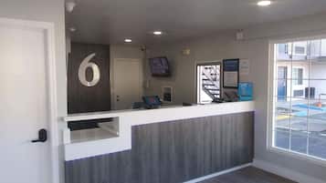 A reception desk with a number '6' sign, a computer, a phone, and a framed welcome sign.