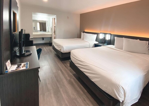 A hotel room with two beds, a desk with a computer, a mirror, and a bathroom visible through an open door. - Functional Unit Ideal for Families & Groups + Free Parking | Pet-Friendly (West Sacramento)