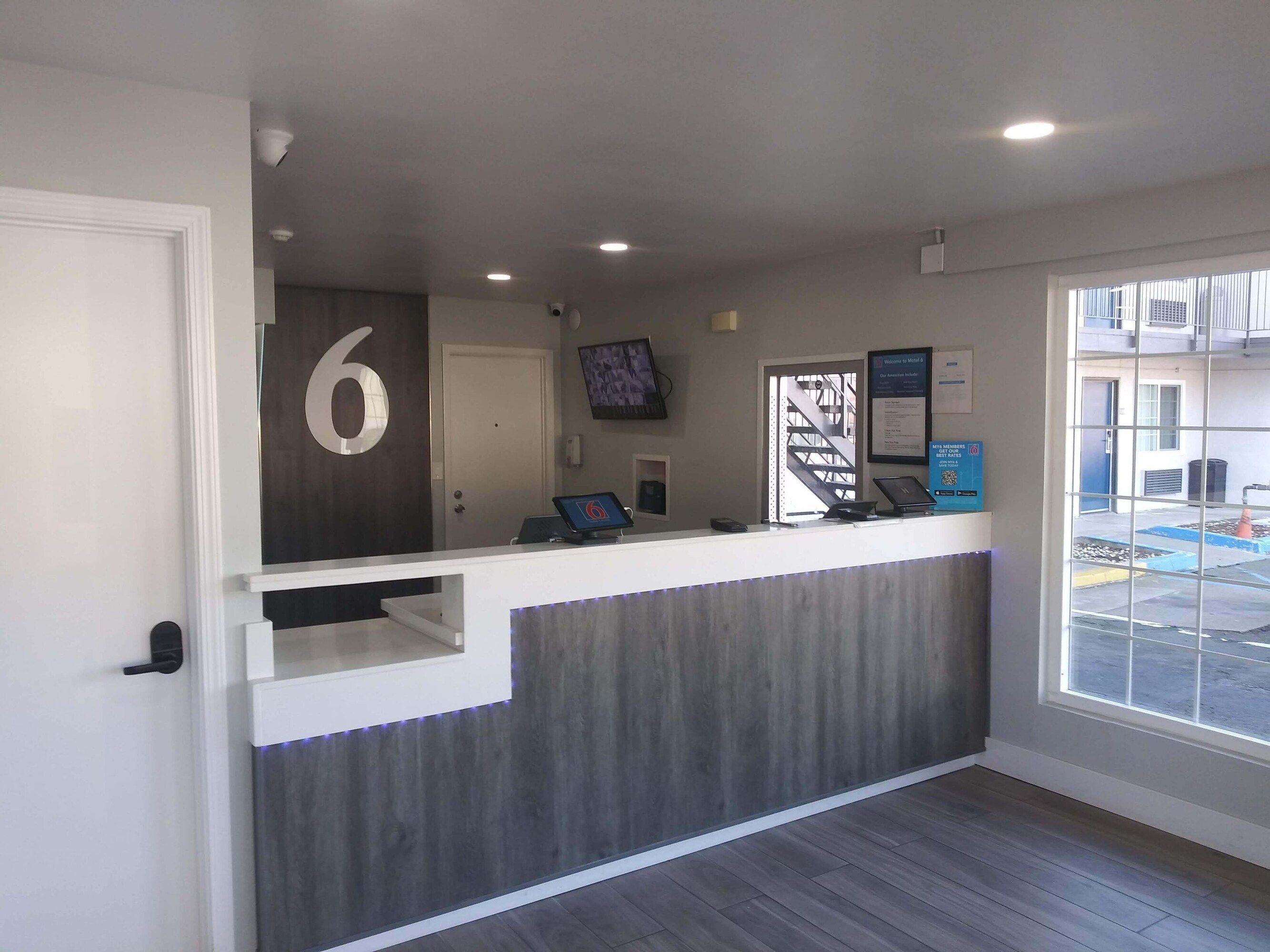 A reception desk with a number '6' sign, a computer, a phone, and a framed welcome sign.