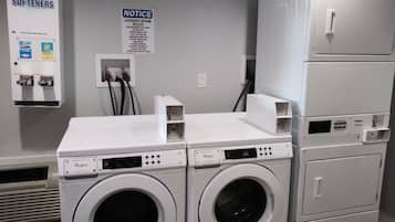 A laundry room with two Whirlpool washers, a notice board, and a utility box.