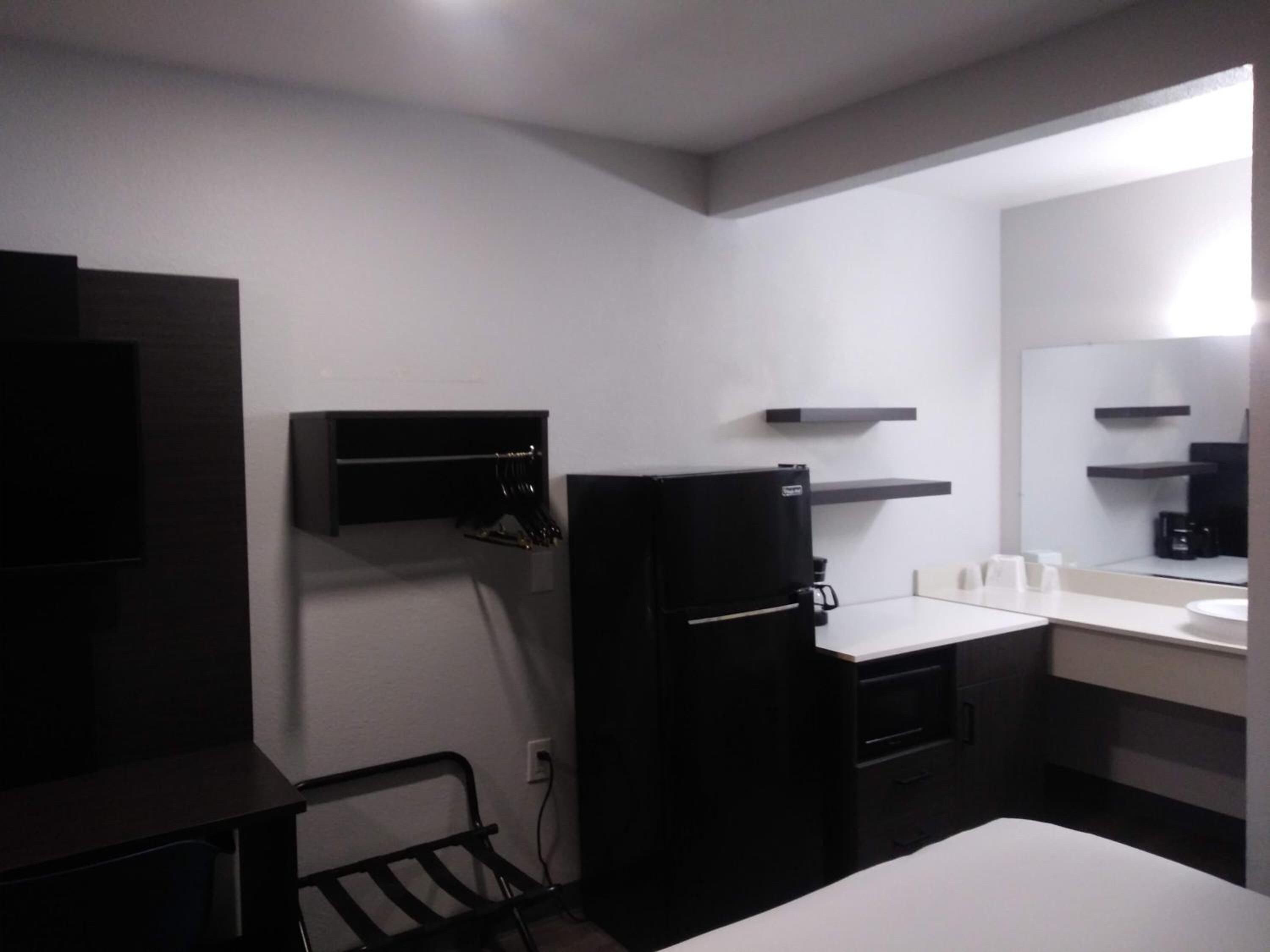 A compact kitchen with a refrigerator, a microwave, a sink, and a small countertop.