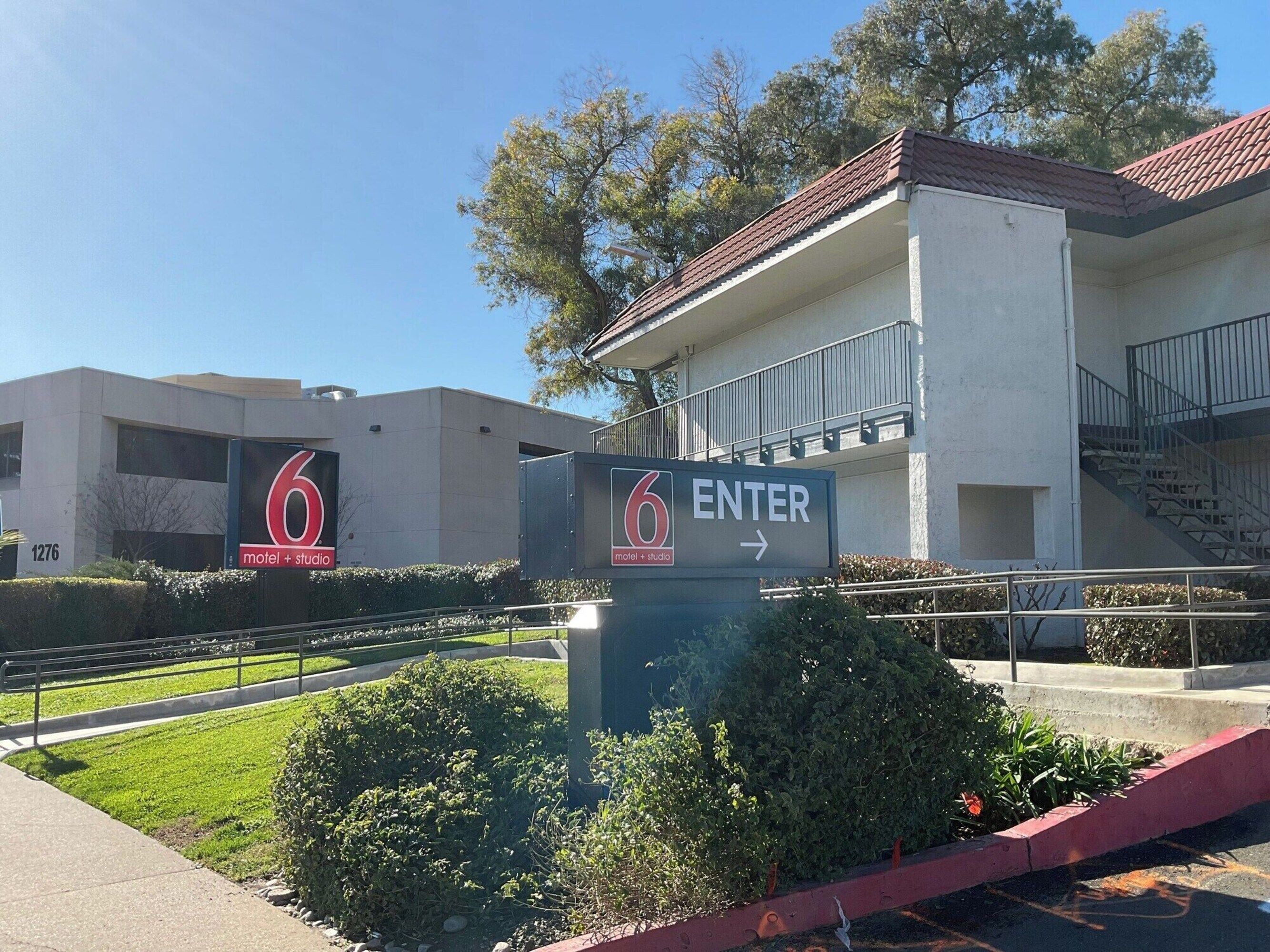 A building with a sign indicating a motel and studio, a staircase, and a clear sky.