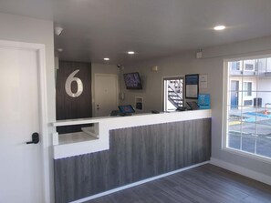 A reception desk with a number '6' sign, a computer, a phone, and a framed welcome sign. - 4 Rooms for Big Groups & Families | 3.1 Mi from California State Capitol Museum (West Sacramento)
