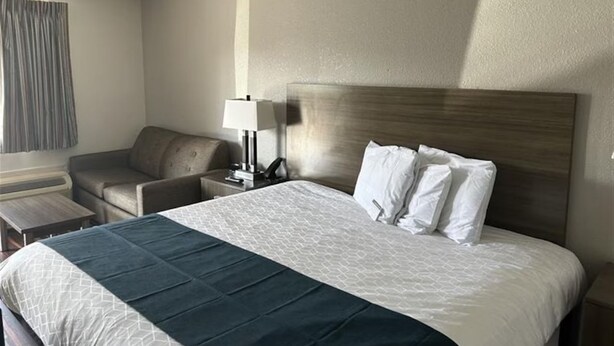 Ein Hotelzimmer mit Bett, Schreibtisch, Stuhl und Lampe.