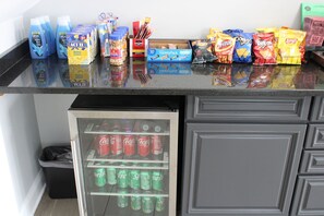 A kitchen counter with various food items and a refrigerator stocked with beverages.