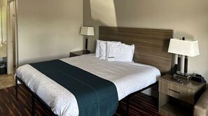 Ein Hotelzimmer mit einem Bett, zwei Nachttischen, einer Lampe und einem Sessel.