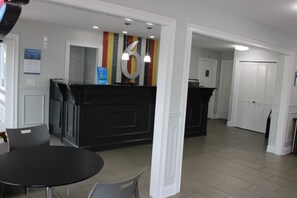 Un área de recepción con un mostrador negro, un gran número 6 en la pared y una puerta que conduce a una habitación.
