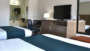 A hotel room with two beds, a desk with a chair, a television, a mirror, and a cabinet.