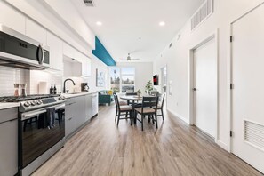 A modern kitchen with a central island, a dining area with a table and chairs, and a view through the window. - The DTLA Haven, 1Mi to Dodger Stadium, Free Parking (Los Angeles)