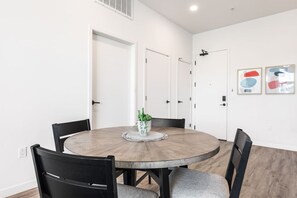 A round dining table with six chairs, a potted plant, and a white door with a handle. - The DTLA Haven, 1Mi to Dodger Stadium, Free Parking (Los Angeles)