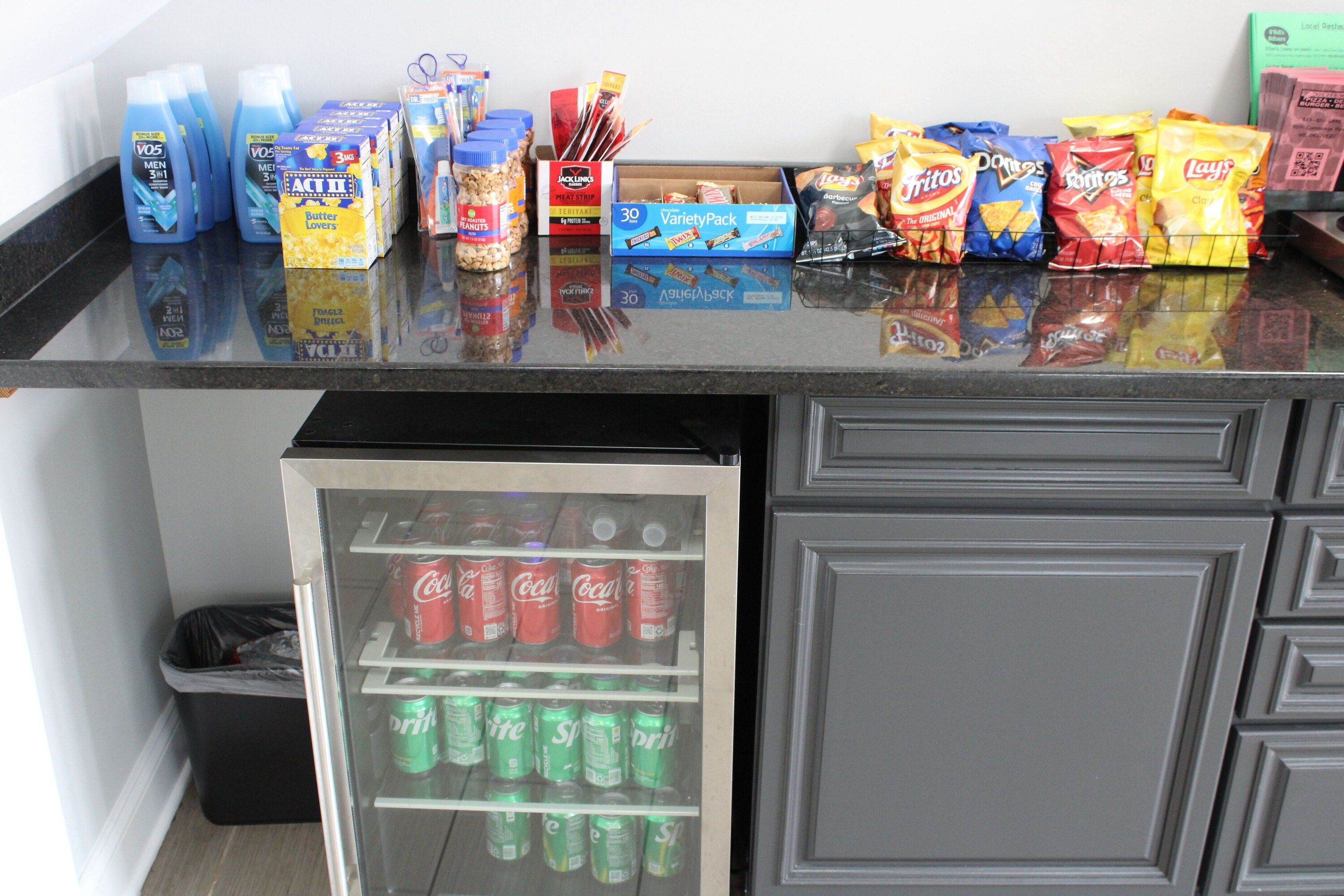 A kitchen counter with various food items and a refrigerator stocked with beverages.