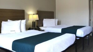 Una habitación de hotel con dos camas, una mesita de noche, una lámpara y una puerta.