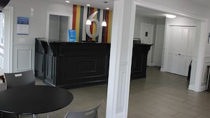 Un área de recepción con un mostrador negro, un gran número 6 en la pared y una puerta que conduce a una habitación.