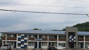 Un motel con fachada a cuadros, varios balcones y un estacionamiento.