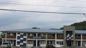 Un motel con fachada a cuadros, varios balcones y un estacionamiento.