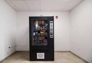A vending machine with snacks and drinks in a hallway. - 3 Pet-Friendly Ingleside Rooms w/ Kitchen, Free Parking | Onsite Pool Access (Ingleside)