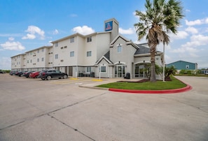 A hotel with a parking lot, a palm tree, and a sign indicating a 0 rating. - 3 Pet-Friendly Ingleside Rooms w/ Kitchen, Free Parking | Onsite Pool Access (Ingleside)